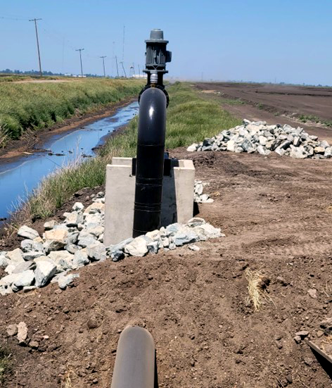 A water recirculation pump installed next to an irrigation ditch.