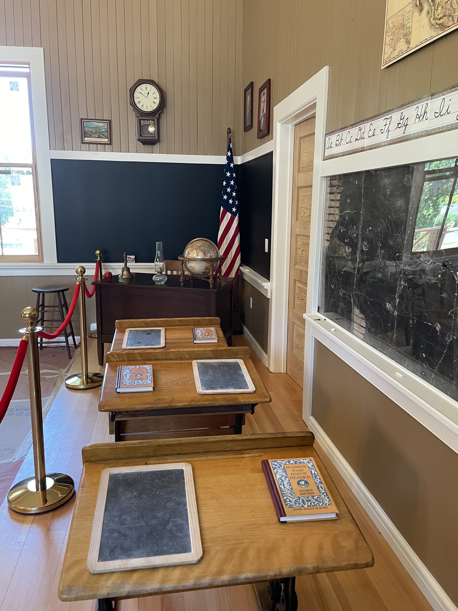 Interior of the 1883 Clarksburg Schoolhouse, which is being restored into a Delta welcome center. Image shows a roped-off area with desks, chalkboards, and other classroom materials. Photo via Friends of the 1883 Clarksburg Schoolhouse.