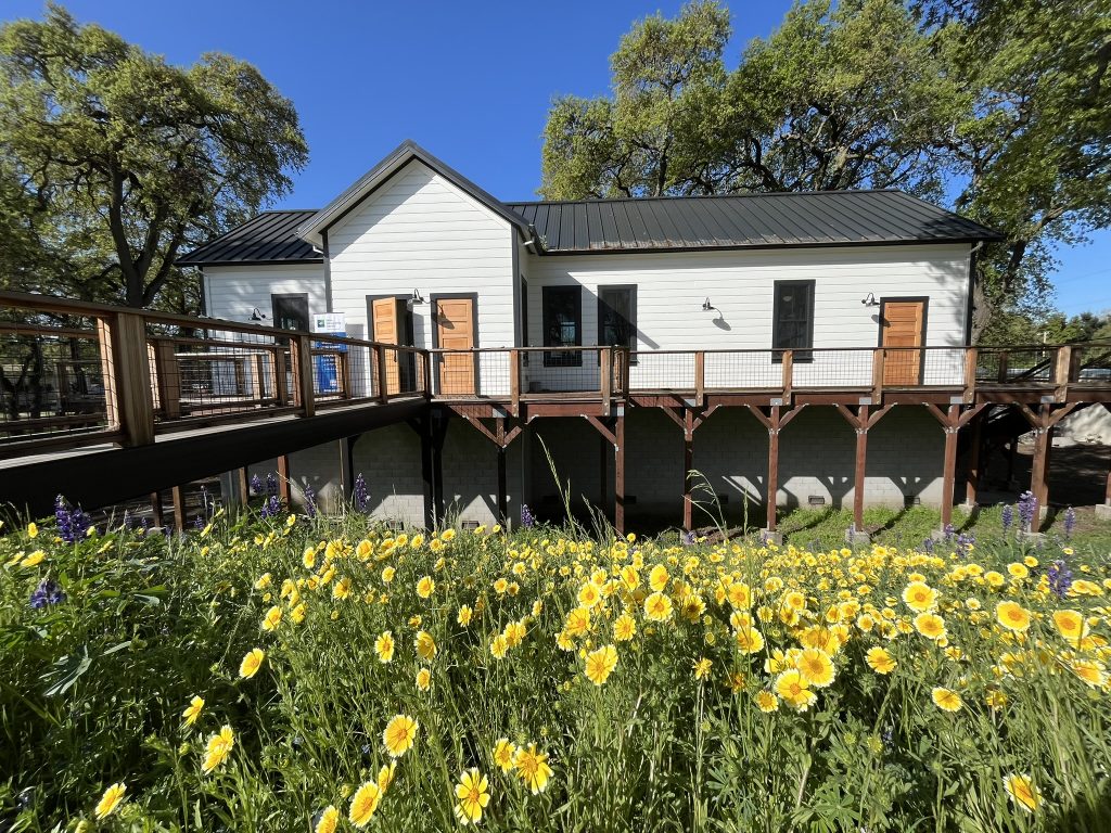Exterior of the 1883 Clarksburg Schoolhouse with flowers in bloom in the foreground